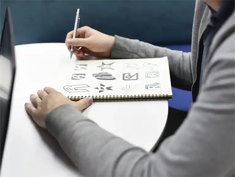 Création de logos blean design Designer créant des esquisses de logos dans un carnet